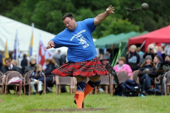 A heavy-events athlete competing in a kilt at a Highland games in Angus